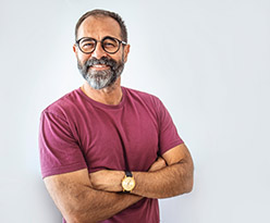 A smiling man standing with his arms crossed.