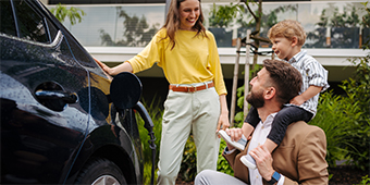 A family is standing next to a car that is being charged