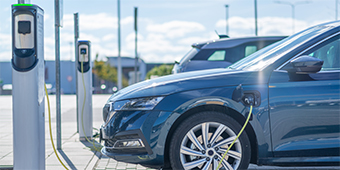 A blue electric car is being charged at a charging station