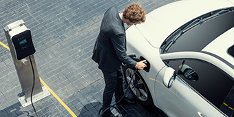 A man is charging his electric car at a charging station