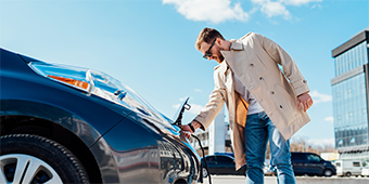 A man is charging his electric car at a charging station