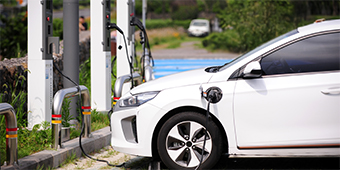 A white electric car is being charged at a charging station