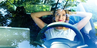 A woman is sitting in a car with her head resting on the back of her seat