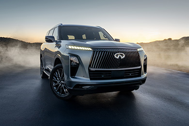 Silver INFINITI QX80 on a misty road at dusk