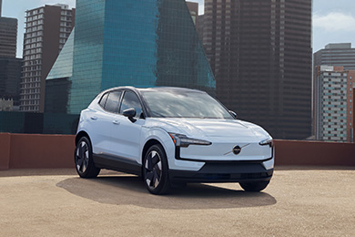 A white Volvo EX30 parked on a rooftop with cityscape behind