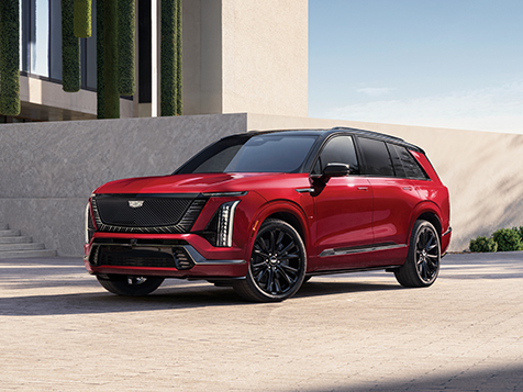 Red Cadillac VISTIQ parked in front of a modern architectural building