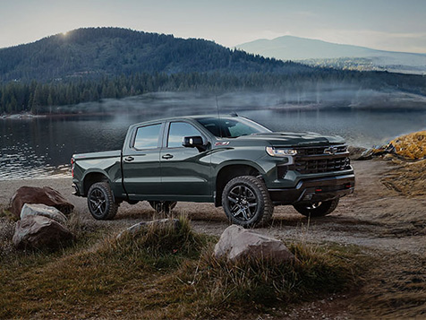 Dark green Chevrolet Silverado LD by a mountain lake at sunrise