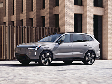 A silver Volvo EX90 parked outside an office building