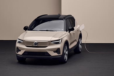 A beige Volvo EX40 plugged into an electric vehicle charger