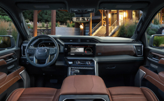 The front interior of a GMC Sierra EV with brown leather seats and a steering wheel shown