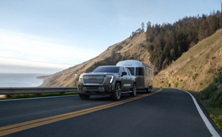 A Chevrolet Sierra EV is towing a trailer down a mountain road