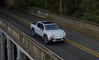 A GMC Sierra EV is parked on a beach next to the ocean