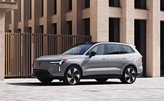 A silver Volvo EX90 parked in front of a building