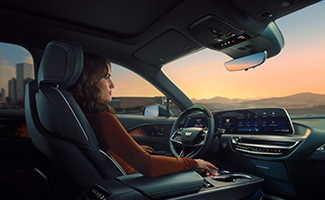 A woman is sitting in the driver's seat of a Cadillac LYRIQ