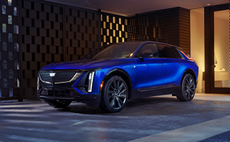 Blue Cadillac LYRIQ is parked in front of a building