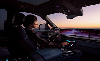 A woman is sitting in the driver's seat of a Cadillac ESCALADE IQ