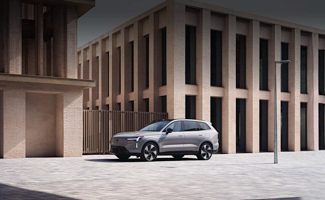 A silver Volvo EX90 parked outside an office building