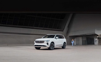 A white Volvo XC90 parked outside an industiral building