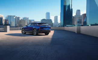 Blue Cadillac LYRIQ parked on a city rooftop overlooking the skyline