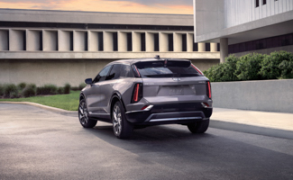 Rear view of a gray Cadillac OPTIQ parked beside a contemporary building