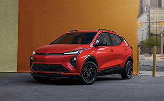 A red Chevrolet Bolt parked in front of a colorful yellow and orange wall